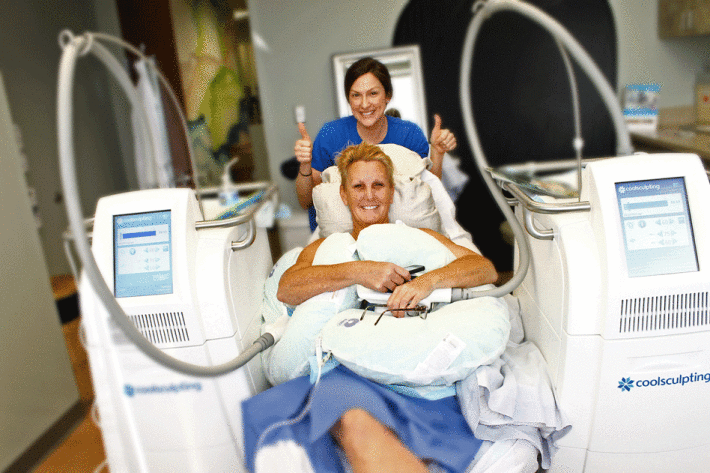 A patient having Coolsculpting on both sides is smiling with Melissa holding up both thumbs behind her