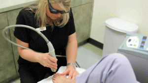 Woman holding laser tip over patient's toes