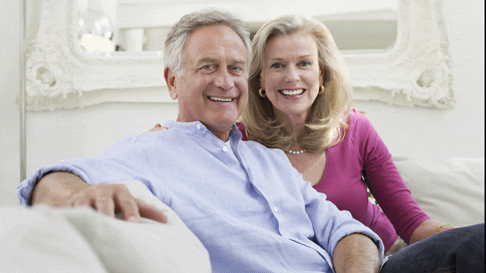 A middle aged couple sitting on a white sofa