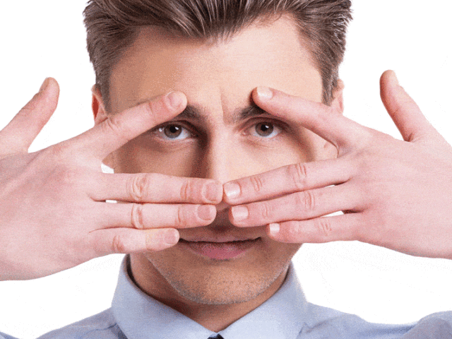 a young man holding hands over face and peeking thru fingers