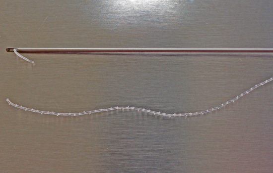 Closeup photo of barbed facial threads and cannula for threadlift
